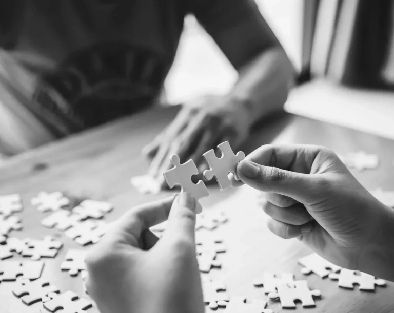 Formation Deux mains tiennent des pièces de puzzle sur une table en bois.